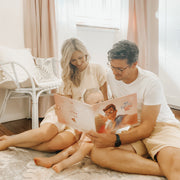 A couple and their baby reading a Hooray Heroes book together