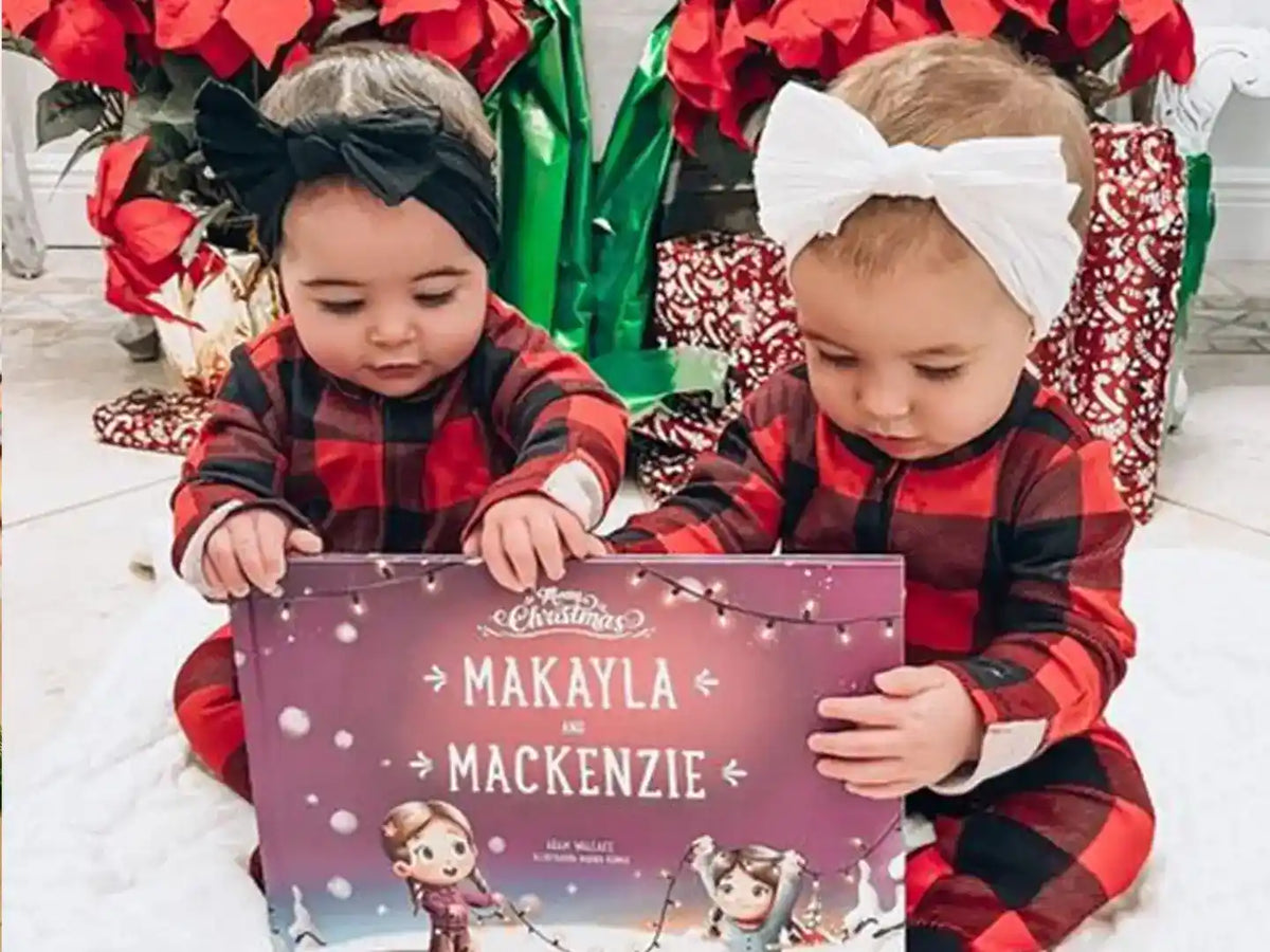 Two little girls with head bows are holding the personalized book for siblings they received as a Christmas present