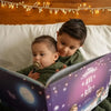 Two boys are sitting on the bed, reading from their custom Christmas storybook made just for them.