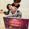 Two brothers smile at their customised Christmas book all about the two of them and their festive adventures.