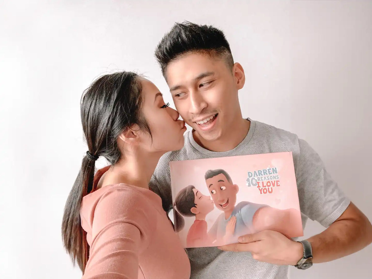 Woman is kissing a man who is holding a unique personalized book for Valentine's Day.