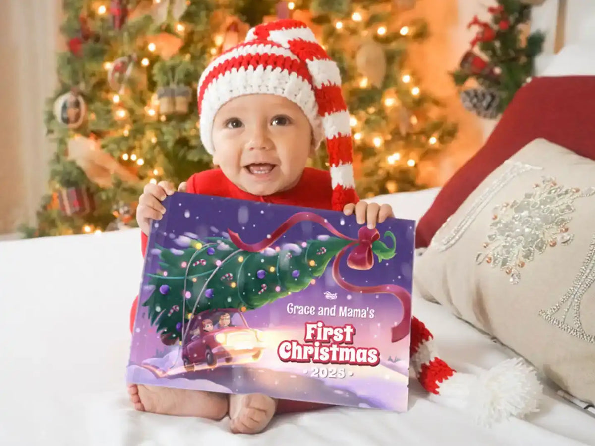 Smiling baby wearing a Christmas hat holding a personalized holiday book titled “Grace and Mama’s First Christmas 2025."