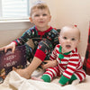 Cute little brothers dressed in Christmas pyjamas are happy about their personalized Christmas book just about them.